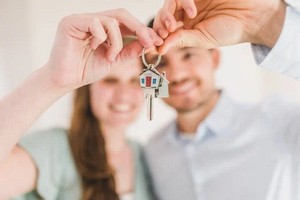 A happy couple proudly holds up a key, celebrating their new home together.