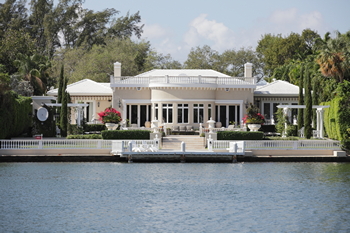 A stunning white house on the shore, with a dock leading out to the water.